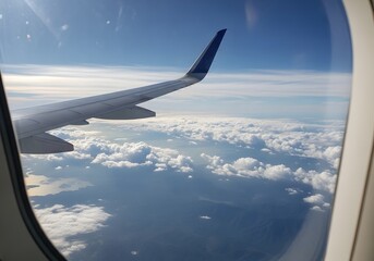 Obraz premium Airplane Wing View from Window Flying Above Clouds with Blue Sky and Sunlight During Travel Journey