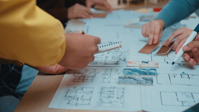 Professionals engage in detailed architectural planning, reviewing blueprints and models in a modern workspace, highlighting teamwork and creative design processes. SACTR