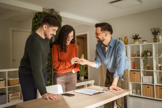 Real estate agent handing over keys to young couple