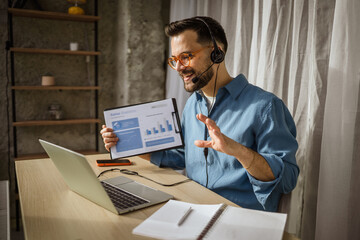 Man working remotely during a video conference holding document