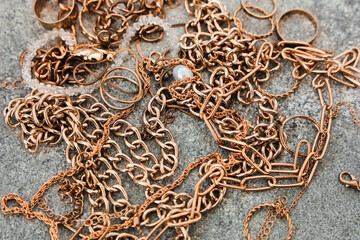 Jewelry pieces are scattered on a gray surface during a close inspection in the afternoon