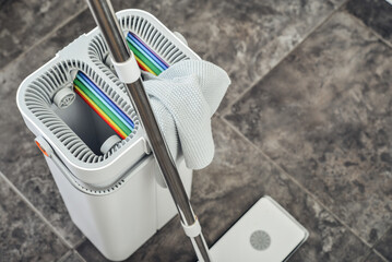 Cleaning supplies: mop, bucket with wringer sitting on tile floor in modern kitchen