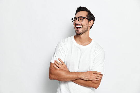 Full body smiling happy cheerful young man wear white t-shirt pose with arms crossed look away isolated on plain solid light background. People lifestyle concept