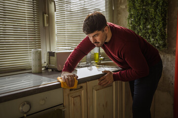 Man intently cleaning kitchen counter with yellow cloth