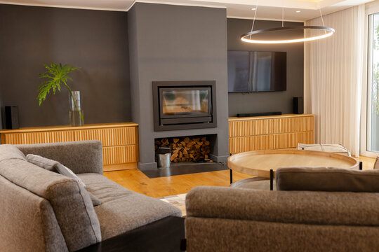 Built-in fireplace sitting in dark-gray chimney breast, showing stacked wood and framing gray sofas