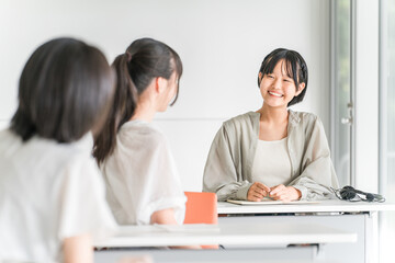 Obraz premium Elementary and junior high school students (friends) talking to the student in front of them during class at school