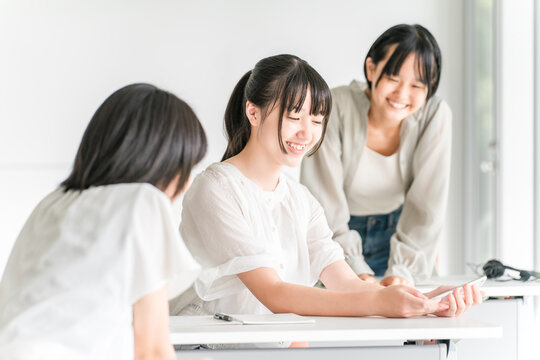 A girl in class chatting with a smile while using her smartphone in a classroom at school