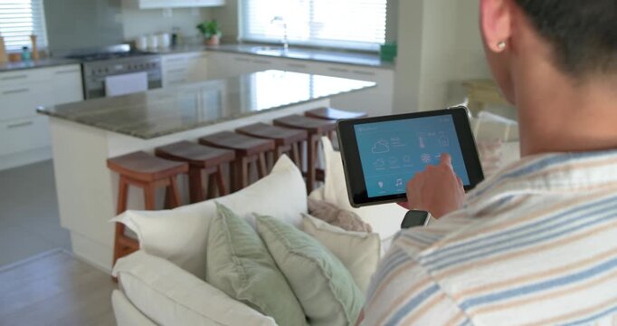 Man is tapping tablet screen, initiating smart home controls and checking weather in living room