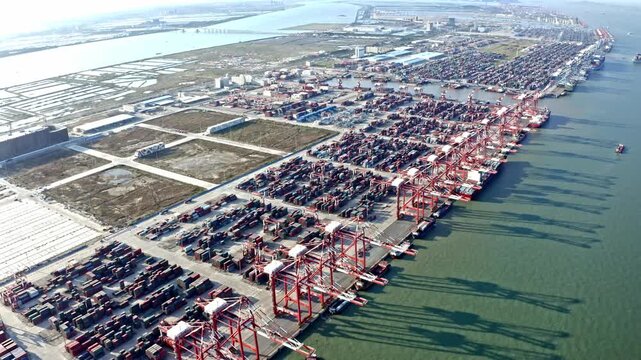 A dynamic aerial time-lapse capturing the pulse of global maritime trade, with massive container ships and synchronized cranes moving under dramatic skies.