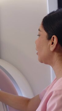 Vertical video: Reaching clinic tech in pink scrub adjusting circular device, smiling, copy space