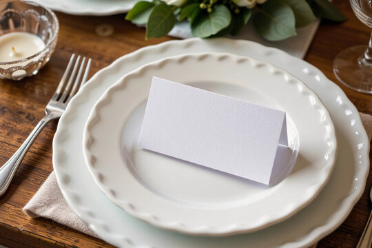 Blank white wedding place card on beige napkin and white plate.