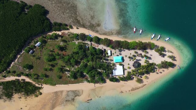 Aerial top down view of tropical paradise  Cowrie island, in Palawan Philippines , coral reef ocean sandy beach and palm tree with traditional boat 