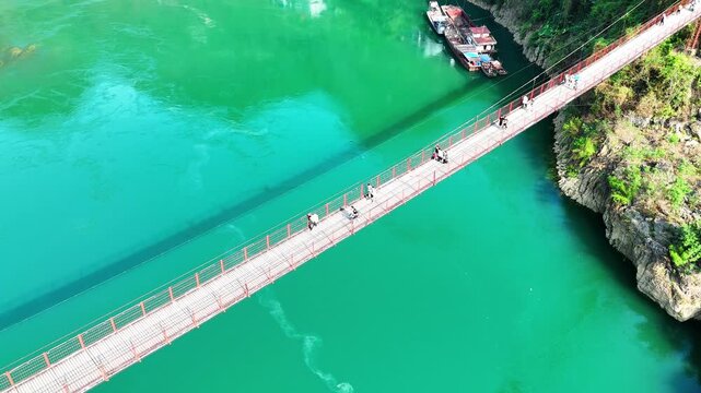 Aerial Journey Home: A Line of Students on a Historic Iron Bridge Over Turquoise Waters