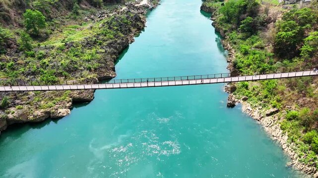 Daily Passage: Several People Crossing the Historic Iron Bridge Over Turquoise Waters, China