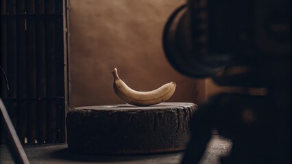 Obraz premium A Single Ripe Banana Curving Gently on a Textured Circular Surface in Warm Lighting