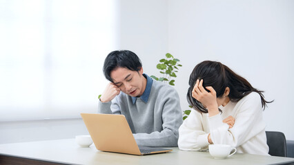 Obraz premium 部屋でノートパソコンを見ながら落ち込む男女カップル