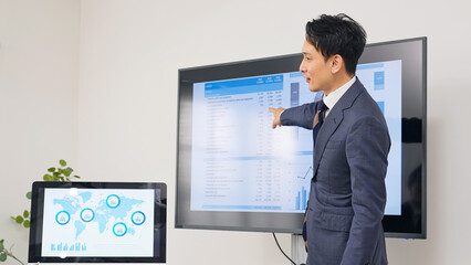モニターを使ってプレゼンテーションする男性ビジネスパーソン