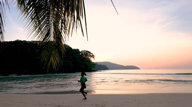 Experience the beauty of Koh Kood, Thailand as a runner enjoys a peaceful morning jog along the sandy beach, framed by palm trees and the gentle waves of the ocean at sunrise.