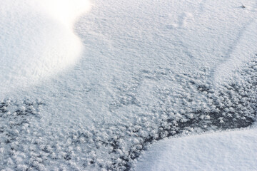 Stunning abstract close-up of sparkling frost crystals on dark ice meeting fresh, bright snow...
