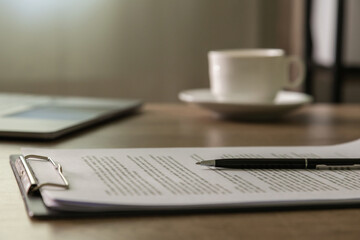a person signing a contract on clipboard at desk, Crop Close up holding a black pen near the signature line. Concept business approval, compliance.