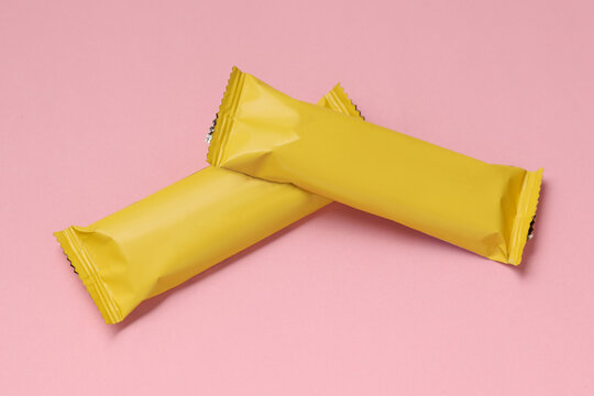 Chocolate bar packs mockup on pink background. Blank yellow candy wrappers