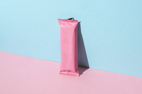 Chocolate bar pack mockup on pink blue background. Blank pink candy wrapper. Creative layout