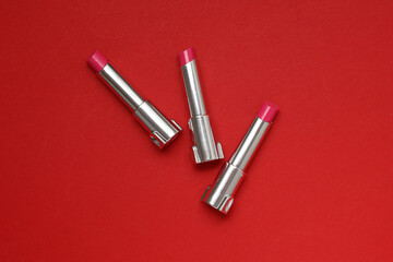 Tubes of pink lipstick on a red background.