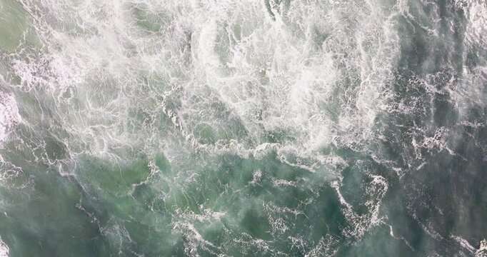 Drone aerial wide of Nazare Portugal Atlantic surf field, rolling swell lines and collapsing breakers creating endless foam, cinematic seascape background for storm and ocean power