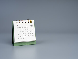Minimal desk calendar showing March 2026 page on gray background, symbolizing time management, event planning, deadline tracking, business scheduling, and monthly organization in modern lifestyle.