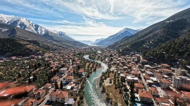 Winter panorama snow-capped peaks, pine slopes, teal river, and a faraway village