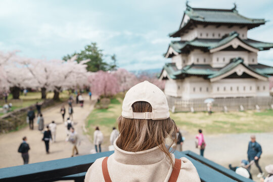 Woman tourist sightseeing Hirosaki Castle with Sakura Cherry Blossom in Spring, happy traveler travel in Hirosaki city, Aomori, Tohoku, Japan. Landmark famous in Japan. Travel and Vacation destination