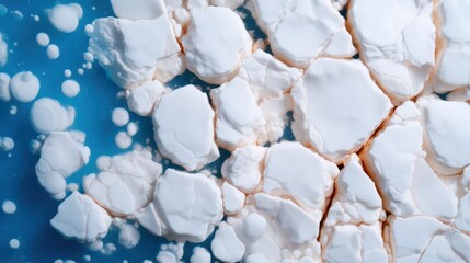 A close-up of cracked white surfaces resembling ice or foam against a blue background, creating a visually striking contrast.