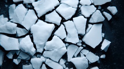 A close-up view of broken ice shards, creating a textured surface with varying shapes and shades of white and light blue.