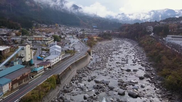Flyover rocky Kiso River at Nagiso, Japan as low cloud fills mtn valley