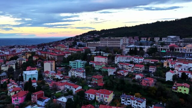 Rising panoramic aerial view of Trieste at dusk.