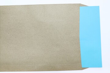 Blue paper pulled out from kraft envelope, white background