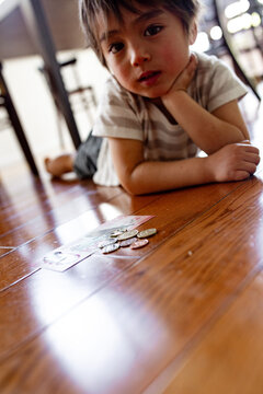 Young boy lying on the floor counting money