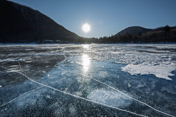 朝日と結氷した赤城山大沼のアイスバブル