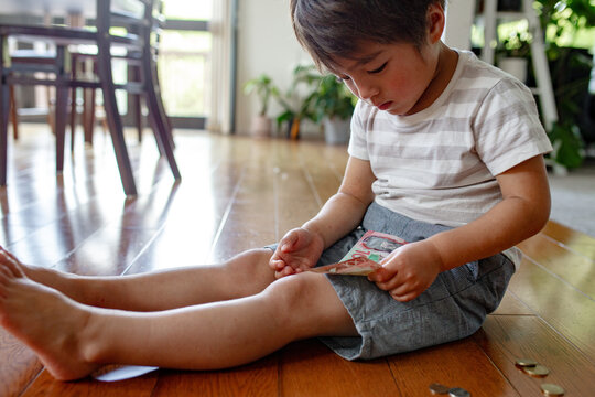 Young boy counting money on the floor