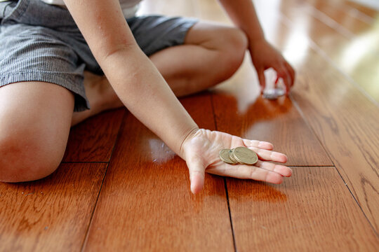 Young boy holding coins in his hand while seated on the floor