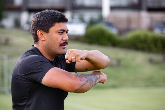 Samoan man posing haka dance move in a green field