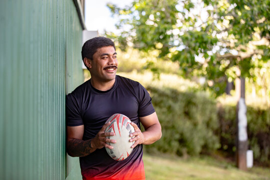 Samoan rugby player leaning against the green wall