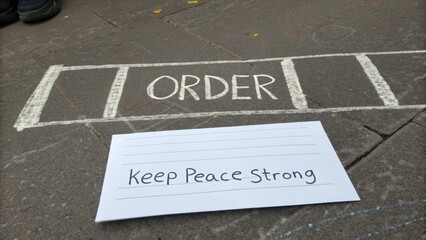 Handwritten Message on Paper and Chalk Drawing on Pavement with Order and Peace Theme for Social Impact Visuals
