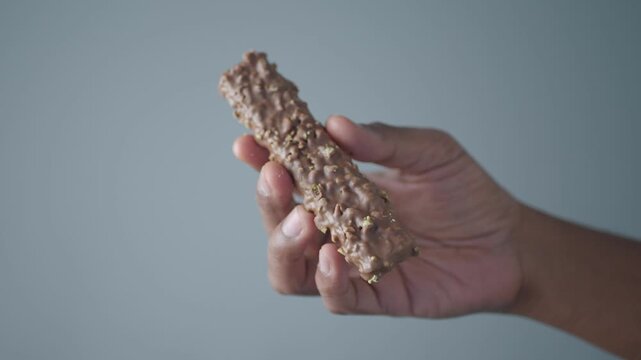 Hand holding a chocolate snack bar in a simple setting