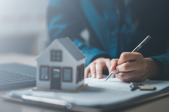 Home buyer calculating mortgage loan and interest rate with documents and house model. Concept of real estate planning, monthly payment analysis, budgeting strategy, and investment decision.
