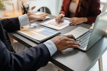 A business meeting scene where professionals review financial charts and exchange insights, highlighting strategic planning and collaborative decision making in a modern office environment.