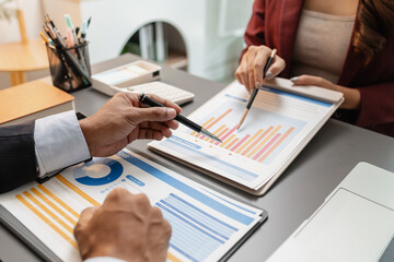 A business meeting scene where professionals review financial charts and exchange insights, highlighting strategic planning and collaborative decision making in a modern office environment.