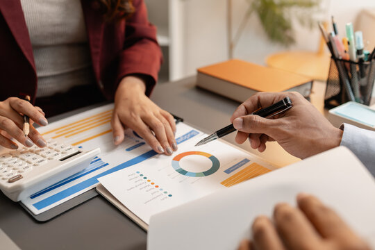 Business professionals meeting at a modern office table, reviewing charts and budget reports while discussing key financial insights and strategic plans for upcoming business decisions.