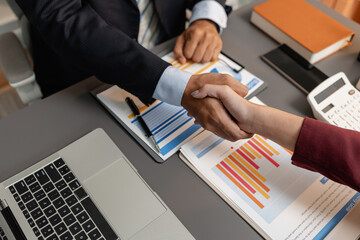 A business meeting scene where professionals review financial charts and exchange insights, highlighting strategic planning and collaborative decision making in a modern office environment.