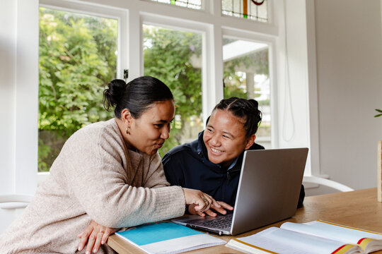 Samoan mum helping teenage daughter with homework using laptop